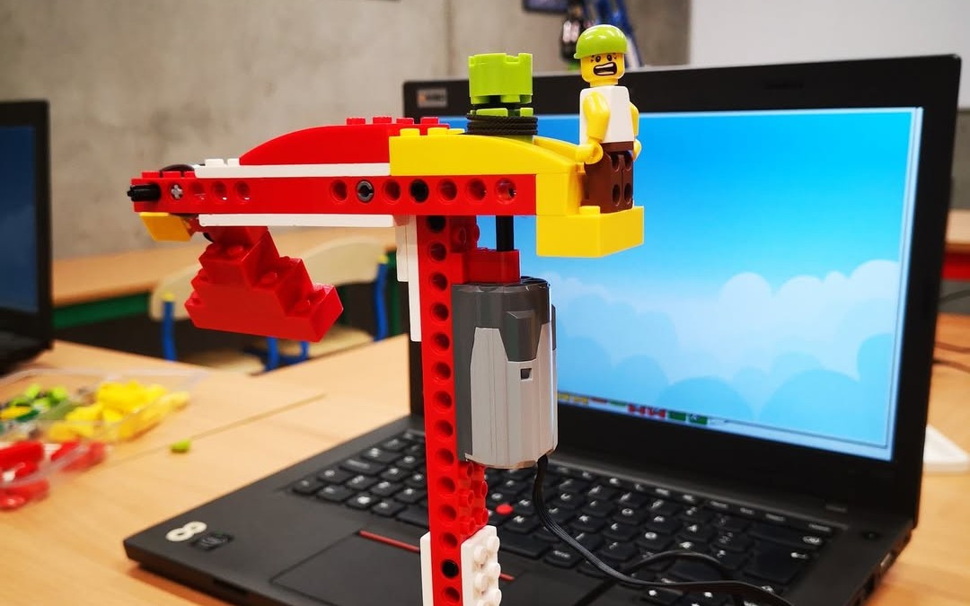 Dzieci budujące robota z klocków LEGO podczas zajęć
